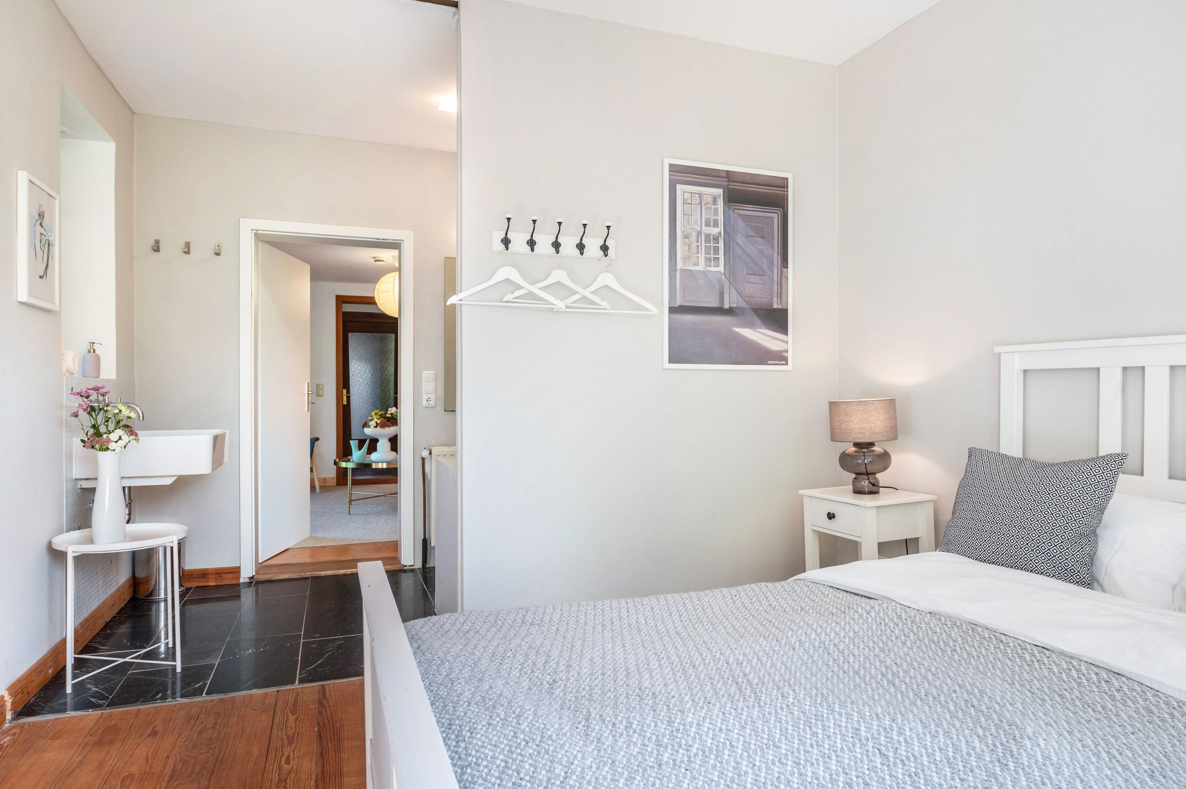 Une chambre à coucher moderne avec un lit, une table de chevet et un luminaire suspendu.