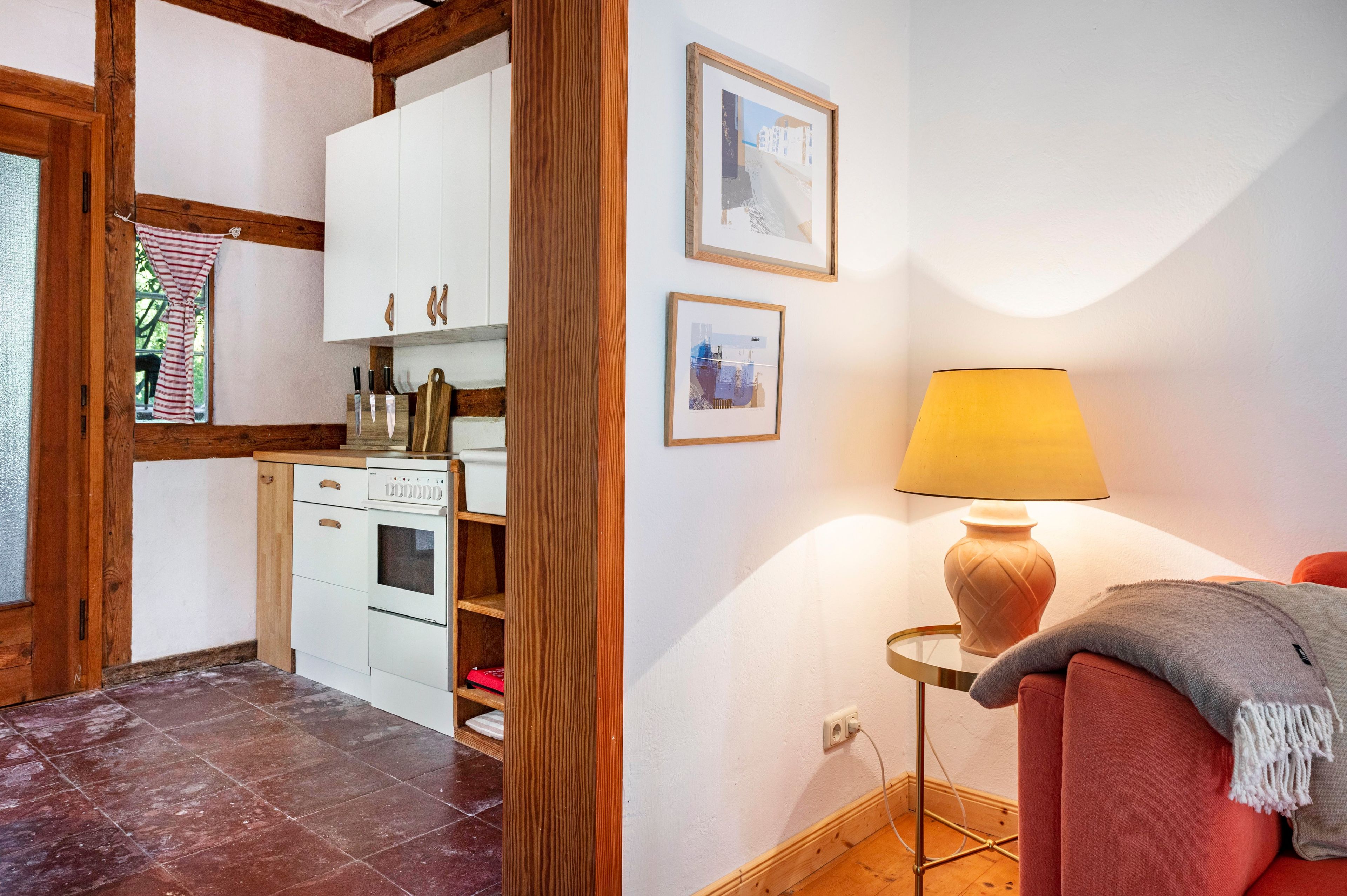 A compact kitchen with white cabinets, a stove, and a wooden floor.