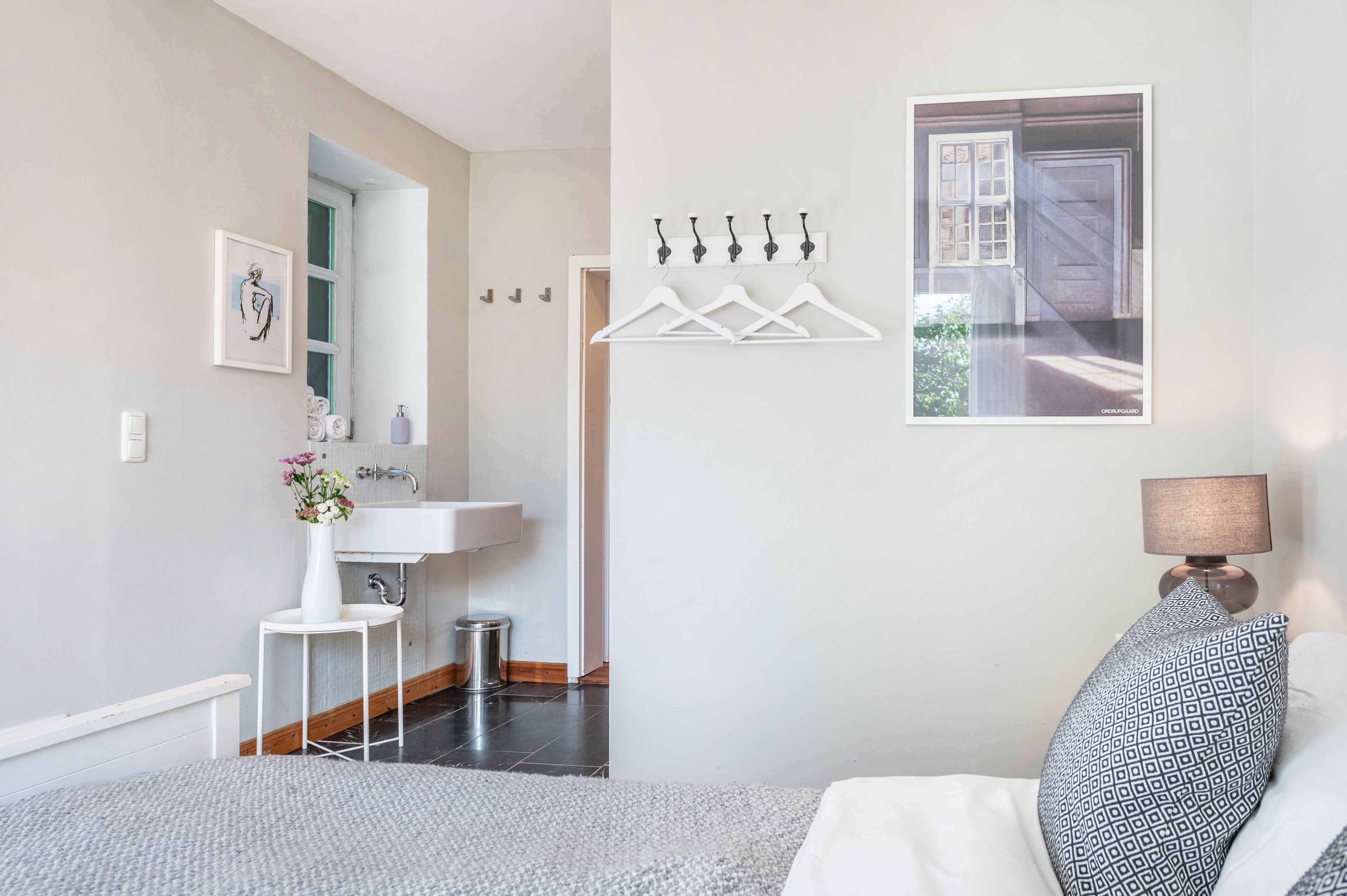 Een moderne badkamer met een witte wastafel, een spiegel en een handdoekhouder.