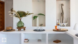A white interior with a wooden beam, a green vase with dried plants, a mirror, and a giraffe sculpture. - Villa ARNELLA by Abahana Villas (Teulada)