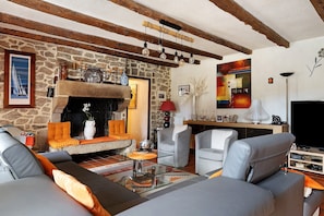 A living room with a stone fireplace, modern furniture, and a television.