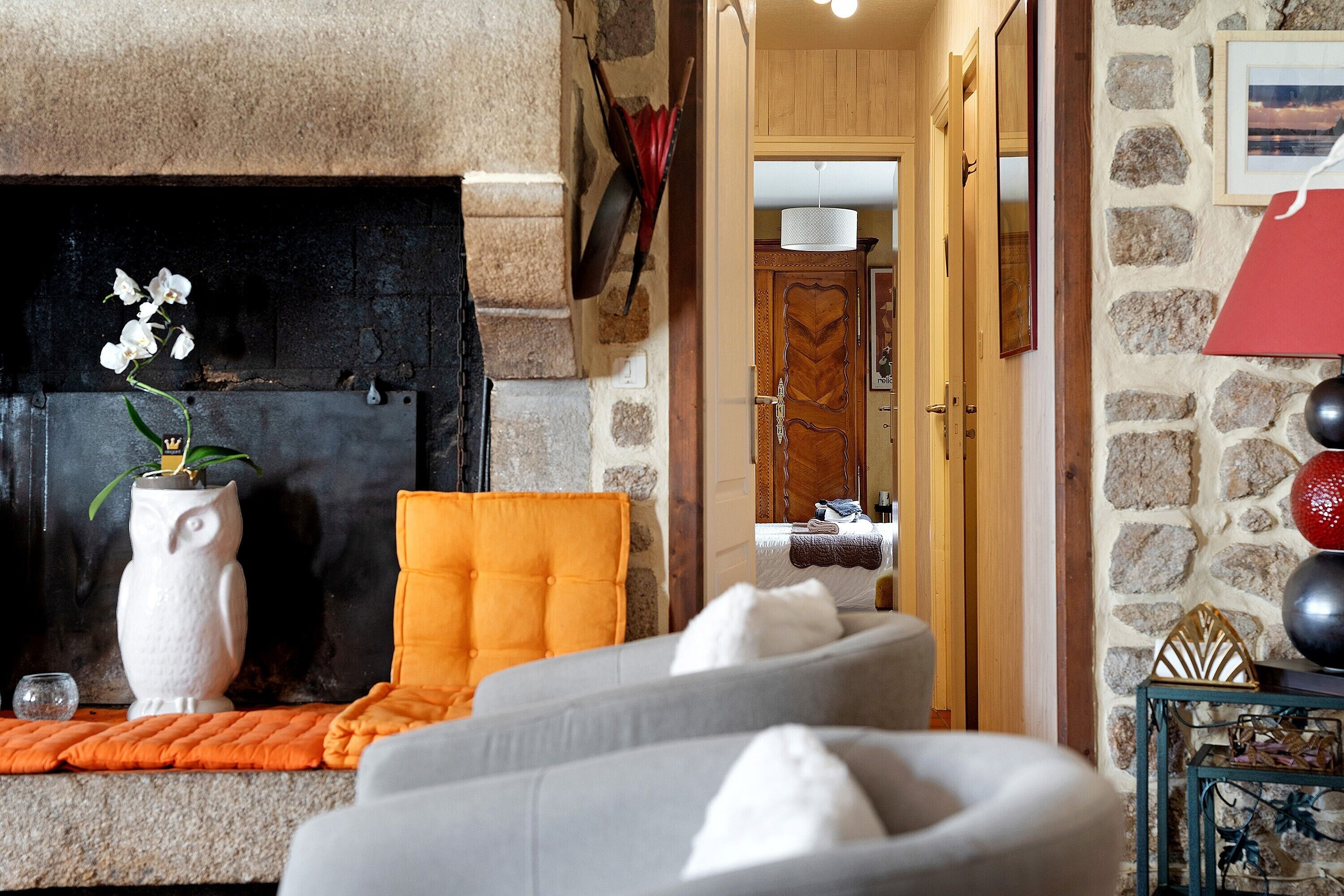 Ein gemütliches Wohnzimmer mit Kamin, einer Couch, einem Sessel und einer dekorativen Vase mit Blumen.