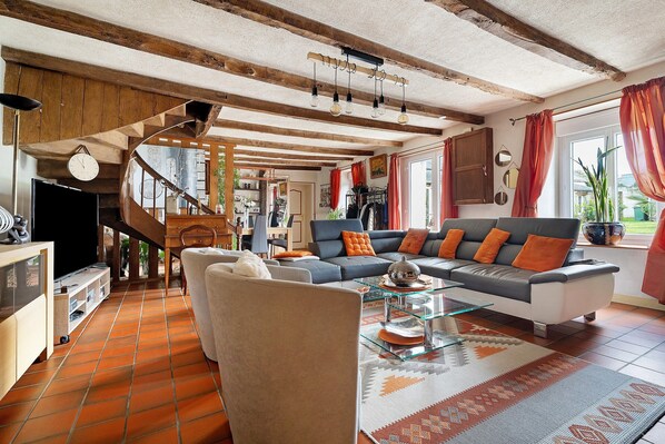 A spacious living area with a staircase, a sofa set, and a dining table.