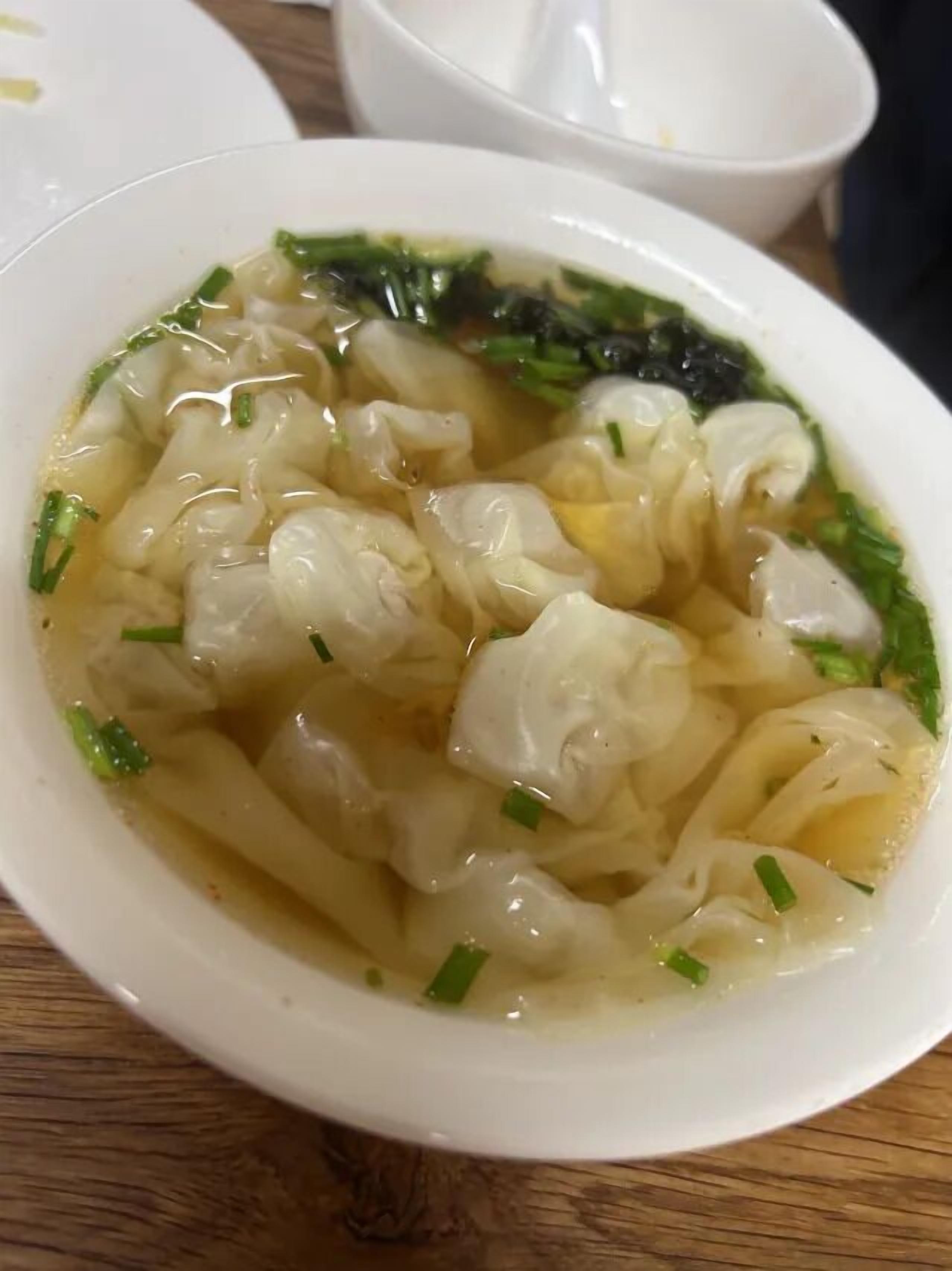 Un bol de soupe contenant des nouilles et des oignons verts.