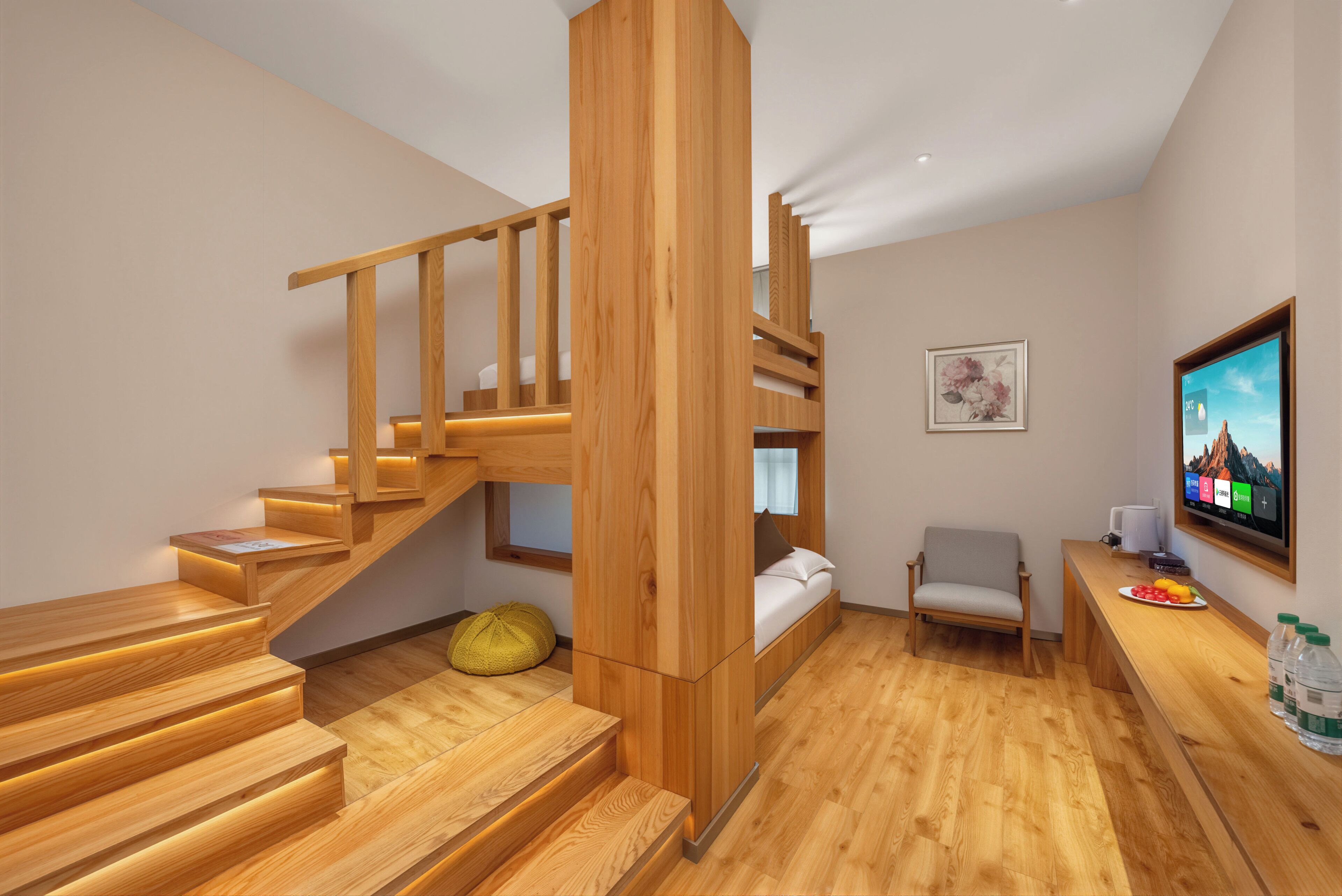 Un interior moderno con una escalera de madera, una cama, una silla, un escritorio con una computadora y una televisión.