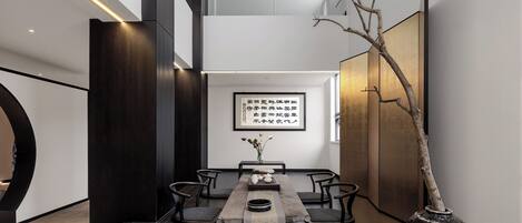 Un interior moderno con una mesa de comedor, sillas, un jarrón con flores y una obra de caligrafía enmarcada en la pared.