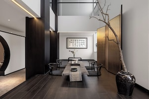 A modern interior with a dining table, chairs, a vase with flowers, and a framed calligraphy piece on the wall.
