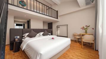 Une chambre d’hôtel moderne avec un grand lit, une petite table, une chaise, un bureau et un balcon.