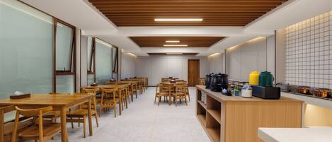 Una cocina moderna con mesas y sillas de madera, una encimera con electrodomésticos y un salpicadero de azulejos.