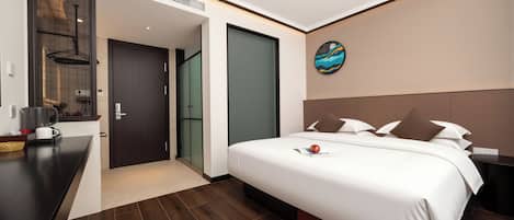 A modern hotel room with a large bed, a desk, and a wall-mounted artwork.