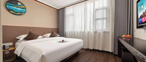 A modern hotel room with a large bed, a desk, a television, and a painting on the wall.