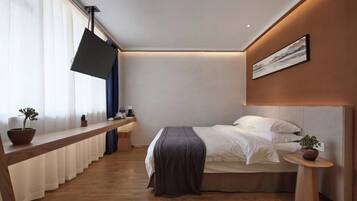 Un dormitorio moderno con cama, mesita de noche y un amplio ventanal con cortinas.