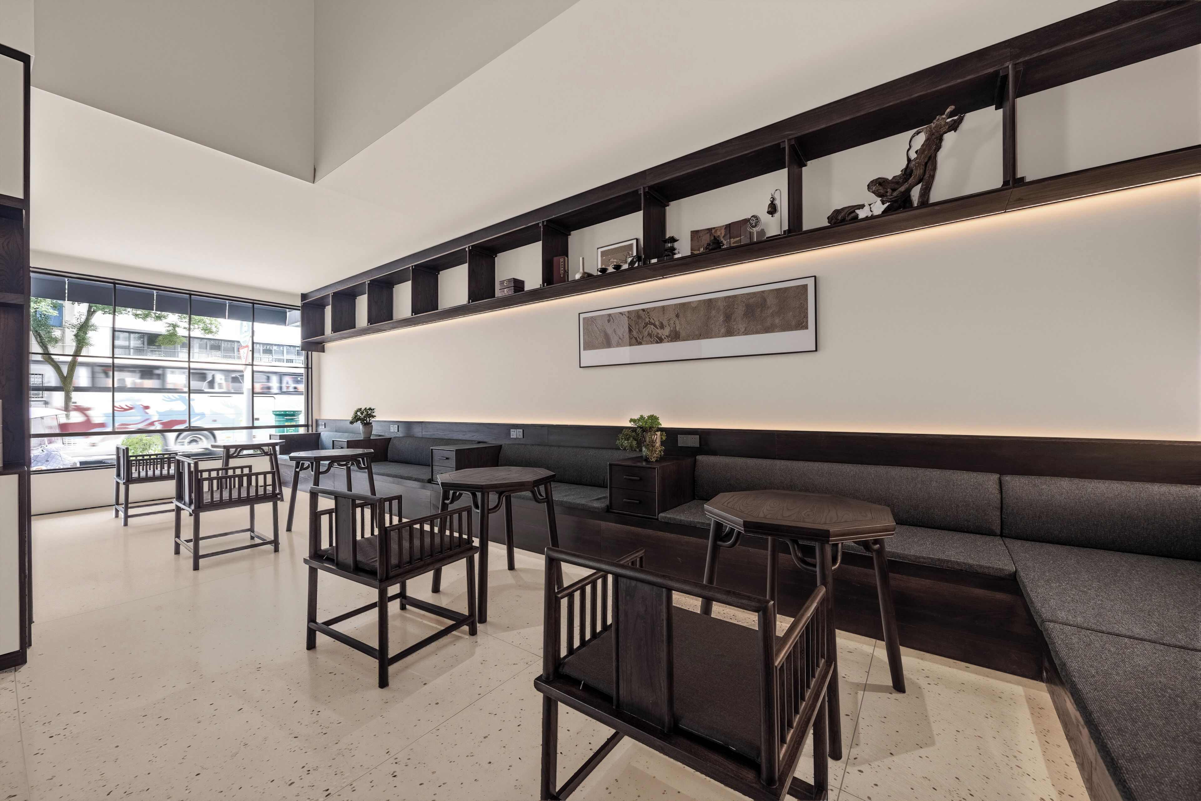 Un intérieur moderne comprenant un espace salon, des tables et une étagère murale agrémentée d’objets décoratifs.