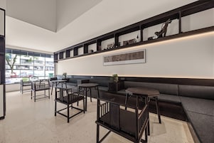 A modern interior with a seating area, tables, and a wall-mounted shelf with decorative items.