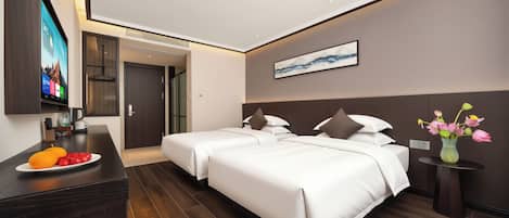 Ein modernes Hotelzimmer mit Bett, Nachttischen, Fernseher und Obstteller.
