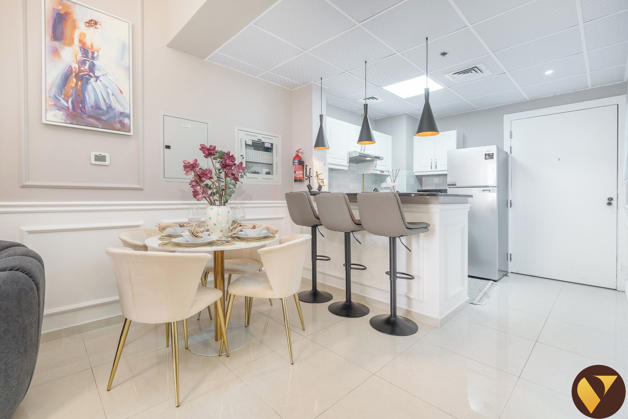 A modern kitchen with white cabinets, a stainless steel refrigerator, and a dining area with a round table and four chairs.