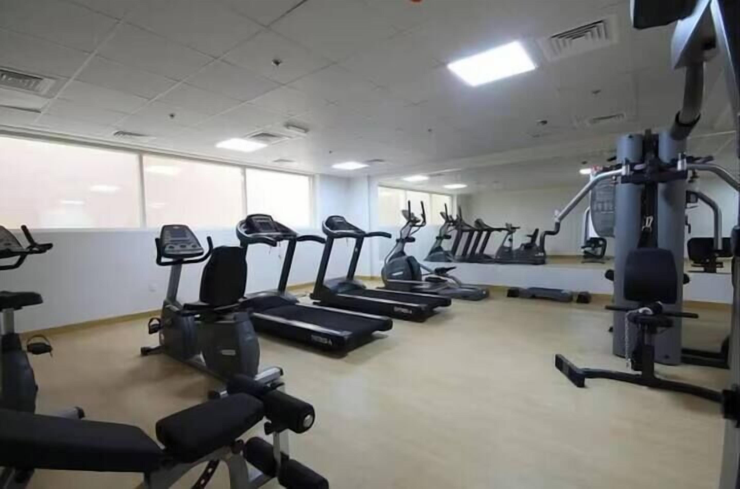 Un gimnasio con cintas de correr, bicicletas estáticas y máquinas de pesas.