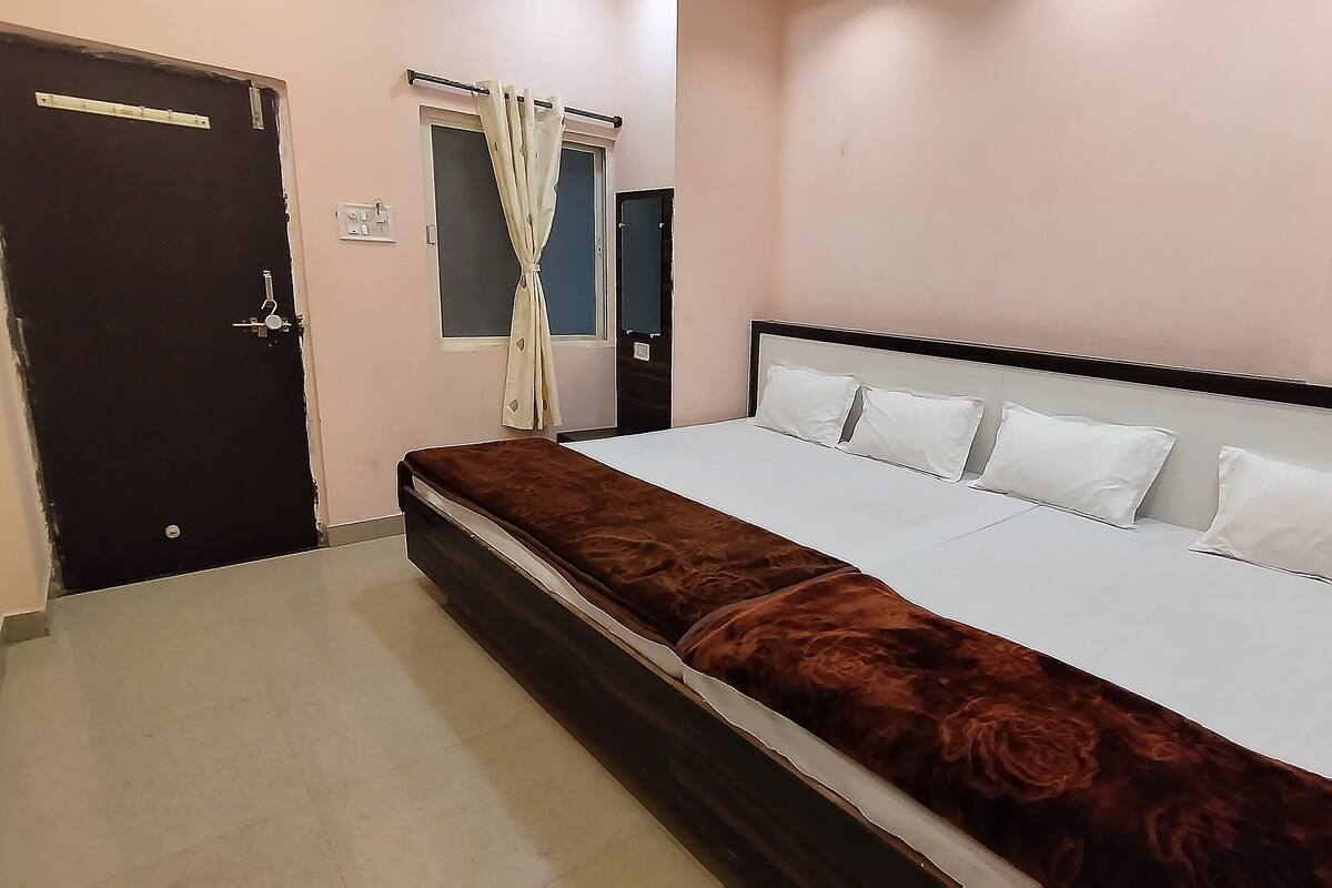 Un dormitorio con cama, ventana con cortinas y puerta.