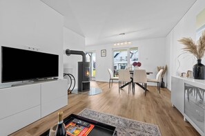 Une cuisine moderne équipée d’un téléviseur à écran plat, d’un poêle à bois et d’un coin repas avec une table et des chaises.