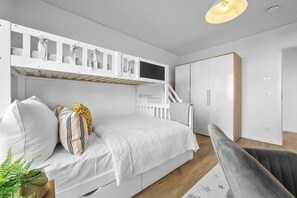 Une chambre moderne avec un lit superposé, un bureau avec un ordinateur, une armoire et un escalier.