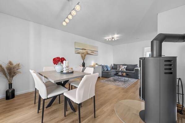 Ein moderner Wohnraum mit Essbereich, einer Couch und einem Kamin.