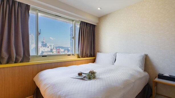 A hotel room with a large bed, a window with curtains, a wooden headboard, and a bedside table with a lamp. - Ximenhotel Xining (Taipei)