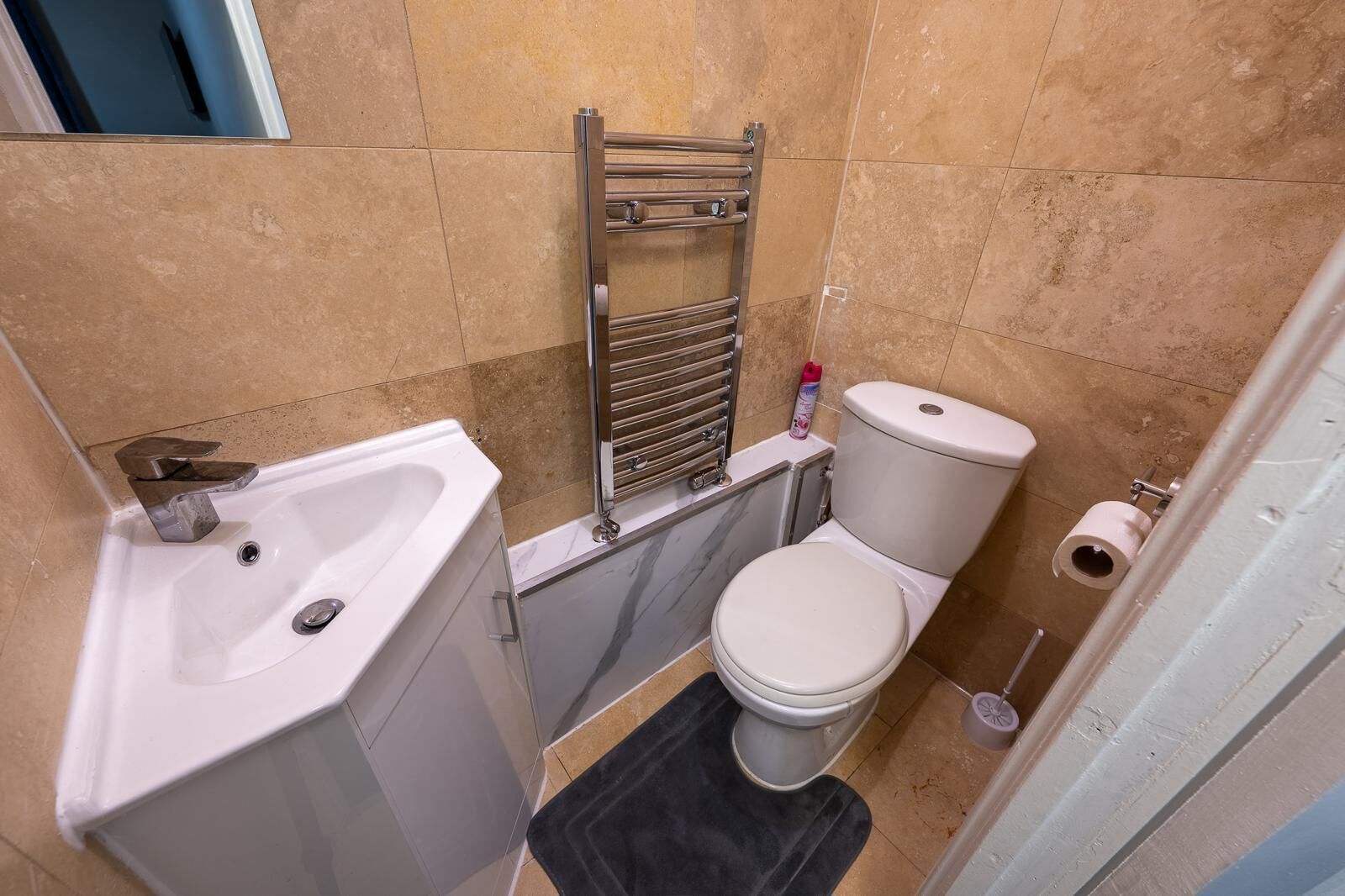 A compact bathroom with a white sink, a toilet, and a towel rack.