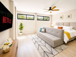 A modern hotel room with a sofa, a bed, a ceiling fan, and a TV screen displaying the Netflix logo. - Coco 5 · 30 m² suite with terrace in Condesa · 1 bath (Mexico City)