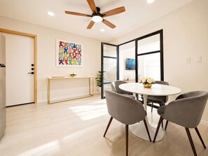 A modern dining area with a round table, grey chairs, a ceiling fan, and a colorful artwork on the wall. - Coco 5 · 30 m² suite with terrace in Condesa · 1 bath (Mexico City)
