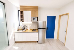 Eine kleine Küche mit einer eingebauten Mikrowelle, einem Edelstahl-Kühlschrank und einer Holzausziehtafel.