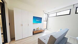A modern living room with a grey sofa, a flat-screen TV mounted on the wall, and a wooden floor. - Stay in Condesa | New, Cozy & Full of Charm (Mexico City)