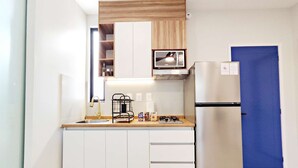 A compact kitchen with white cabinets, a stainless steel refrigerator, a built-in microwave, and a wooden countertop. - Stay in Condesa | New, Cozy & Full of Charm (Mexico City)