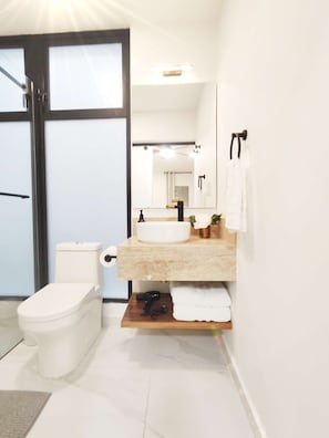 Un baño moderno con inodoro, lavamanos y espejo.
