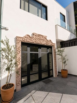 A modern building with a large glass entrance, decorative wall carvings, and potted plants. - Coco 1 · 20 m² studio with terrace in Condesa · 1 bath (Mexico City)