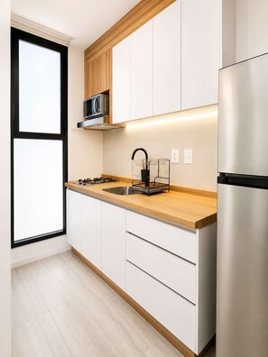 A modern kitchen with white cabinetry, a stainless steel refrigerator, a wooden countertop, and a black faucet. - Coco 1 · 20 m² studio with terrace in Condesa · 1 bath (Mexico City)