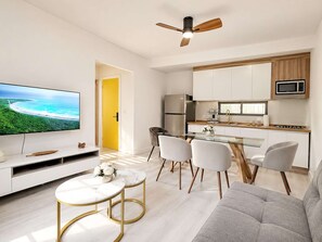 A modern living room with a flat-screen TV, a sofa, and a dining area with chairs and a table. - Coco 3 · 40 m² suite with balcony and terrace · 1 bath (Mexico City)