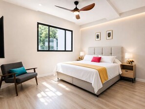 A modern bedroom with a large bed, a chair, a nightstand, and a ceiling fan. - Coco 3 · 40 m² suite with balcony and terrace · 1 bath (Mexico City)