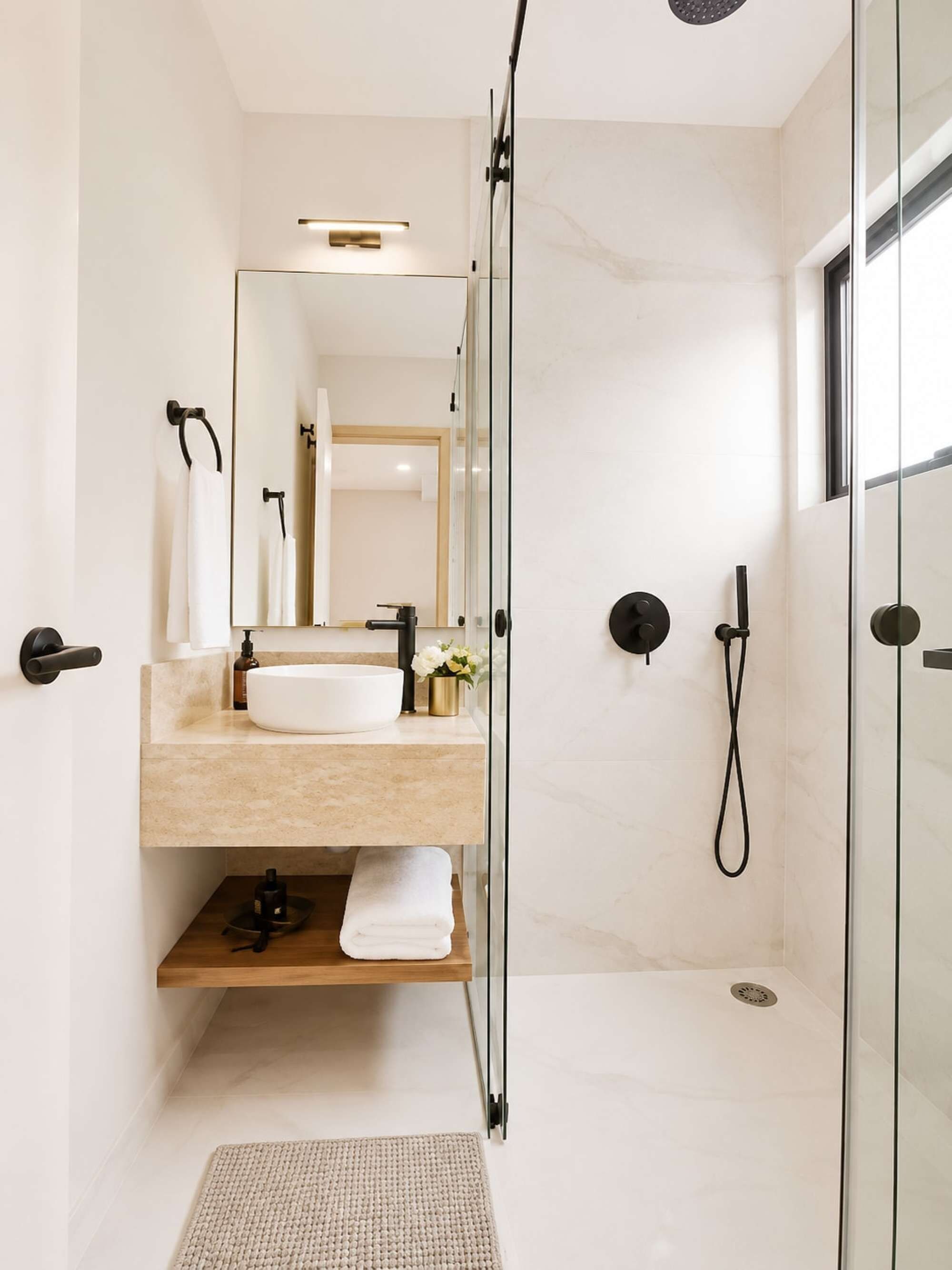 A modern bathroom with a glass-enclosed shower, a vanity with a sink, and a mirror.
