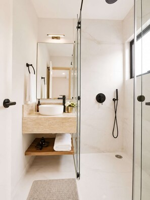 A modern bathroom with a glass-enclosed shower, a vanity with a sink, and a mirror. - Coco 3 · 40 m² suite with balcony and terrace · 1 bath (Mexico City)