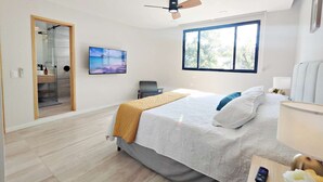 A modern bedroom with a bed, a ceiling fan, a TV, and a window with a view of trees. - Modern Condesa 1BR | King & Sofa Bed | Brand New (Mexico City)
