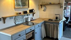 A compact kitchen with a wooden countertop, grey cabinets, a sink, and a small window. - Waterside Cabin | Cavan Lakes | Hot Tub (CN)