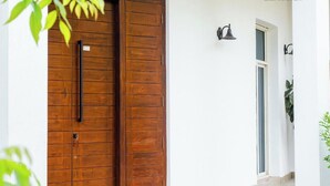 Une porte en bois avec une poignée, une petite enseigne et un luminaire fixé au mur.
