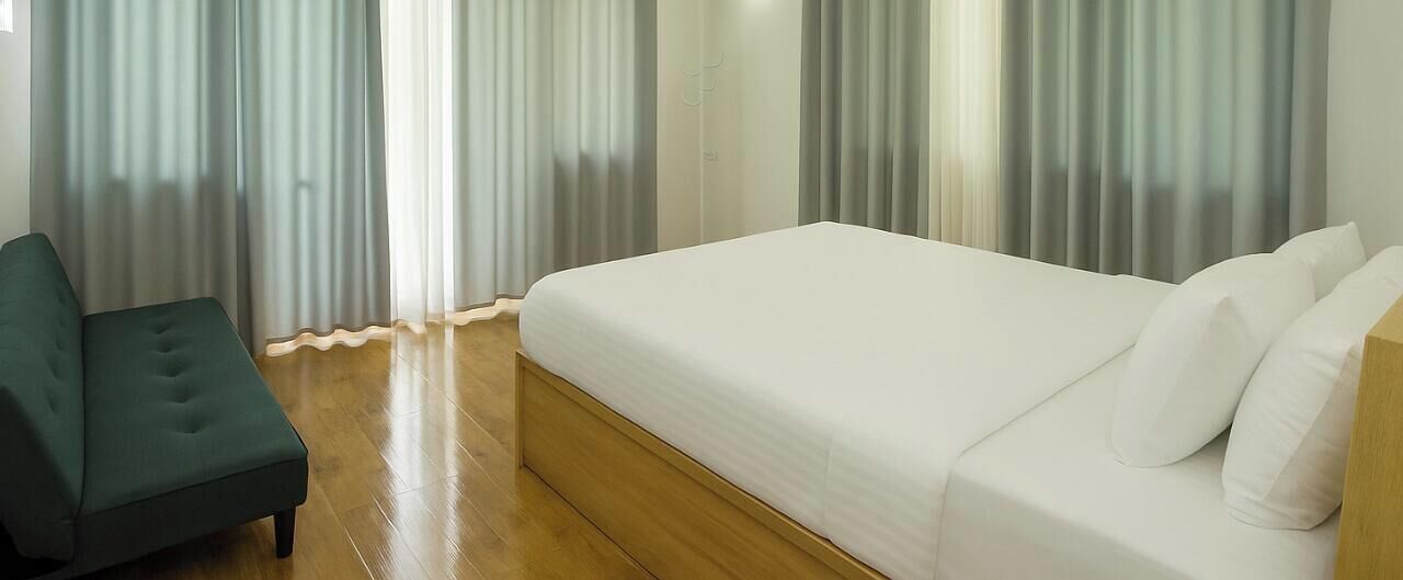 Ein Hotelzimmer mit einem Bett, einem grünen Sessel und Holzboden.