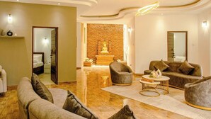 Un salon moderne avec un canapé, des fauteuils, une table basse et une statue de Bouddha en arrière-plan.