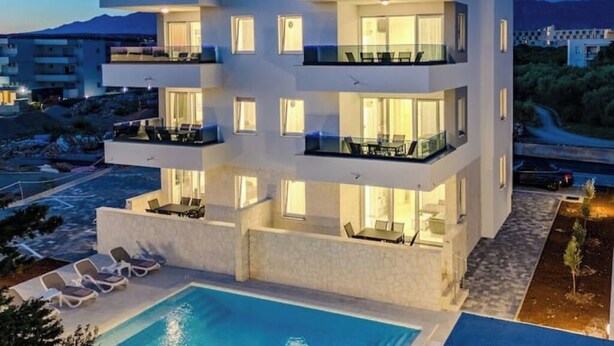Un immeuble moderne à plusieurs étages, doté de balcons, d’une piscine et offrant une vue sur le paysage environnant.