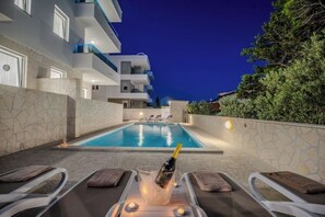 Área da piscina com espreguiçadeiras e uma garrafa de champanhe.