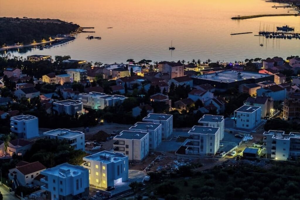 Une ville côtière au crépuscule, avec des immeubles résidentiels et une marina.