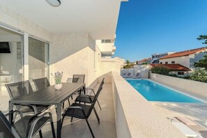 Uma área moderna para refeições ao ar livre com piscina e vista para as casas vizinhas.