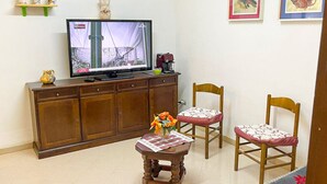 A living room with a television, a wooden cabinet, two chairs, a small table with a vase, and artwork on the wall. - Casa vacanze - Villa Stefania 1 (Pescocostanzo)