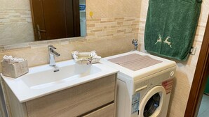 A bathroom with a sink, mirror, towel rack, and a washing machine. - Casa vacanze - Villa Stefania 1 (Pescocostanzo)